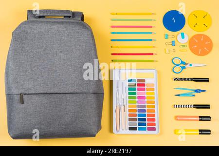 Education, learning, back to school background. Knolling composition with gray backpack and different school stationery supplies on yellow background Stock Photo
