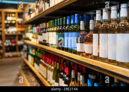 Alcohol business concept, wine bottles in a row on the shelf of wine shop. Stock Photo