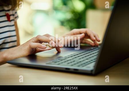 Hands typing on laptop keyboard. Close up shot of woman using laptop in cafe Stock Photo