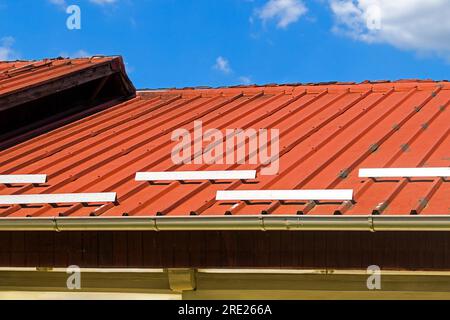 Ceramic orange roof tiles on top of the house with blue clouds in background Stock Photo