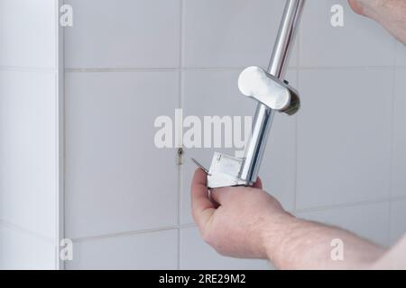 https://l450v.alamy.com/450v/2re29m2/replacing-the-rack-and-holder-for-the-shower-on-the-wall-in-the-bathroom-unscrewing-the-screws-from-the-wall-fixing-2re29m2.jpg