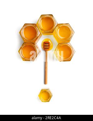 Creative composition of honey in open jars in the form of honeycombs and a wooden dipper on a white background top view. Stock Photo