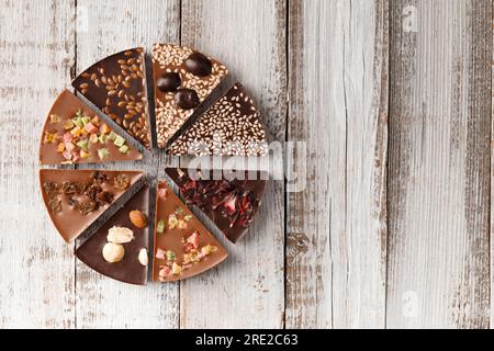 Creative composition chocolate in the shape of a pizza with candied fruits, nuts, dry berries, chocolate pizza and ingredients on a wooden background Stock Photo