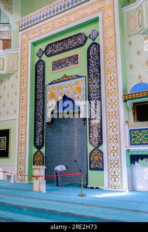 Kazakhstan, Almaty. Baiken Mosque Interior Showing Mihrab and Worshiper Praying. Stock Photo