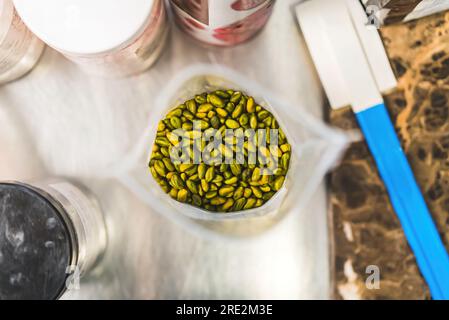 Top shot of open plastic bag filled with whole shelled green pistacchios. Pistachios presented on kitchen counter with confectionery appliances and ingredients. High quality photo Stock Photo