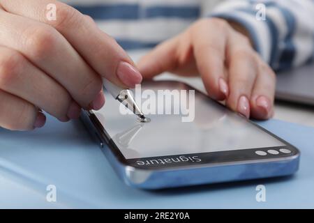 Electronic signature. Woman using stylus and mobile phone, closeup Stock Photo