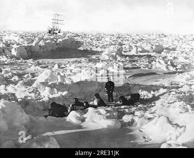 Antarctica:  1915 British explorer Sir Ernest Shackleton's ship, the Endurance, caught in the ice of the Weddell Sea, where it eventually sank. In the foreground is one of the expedition members out with a dog sled team on a food foraging expedition. Stock Photo