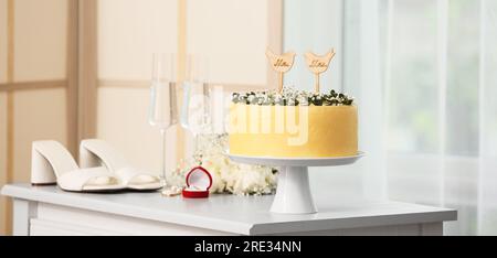 Stand with beautiful wedding cake on table in room Stock Photo