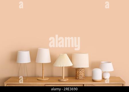 Set of different table lamps on wooden cabinet near beige wall Stock Photo