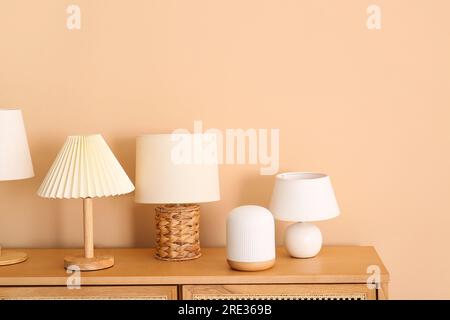 Set of different table lamps on wooden cabinet near beige wall Stock Photo