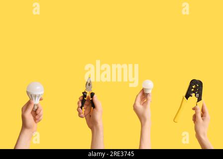 Electrician hands with light bulbs and tools on yellow background Stock Photo