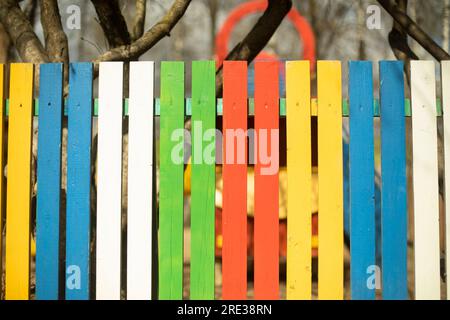 Cheerful fence made of colored boards. Fence in park. Creative design solution. Bright colors. Stock Photo