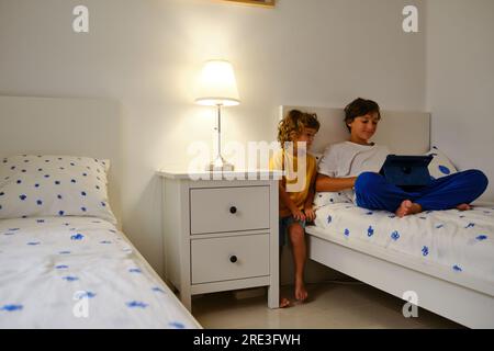 Brothers using tablet in bedroom Stock Photo