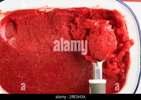 Strawberry granita or fresh berry sorbet in white rustic bowl on old wooden table background. Texture of ice cream or sorbet. Ice cream with strawberr Stock Photo