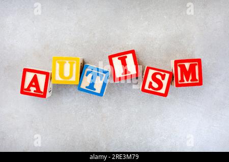 Autism spelled out in kids building blocks on mottled grey. Stock Photo