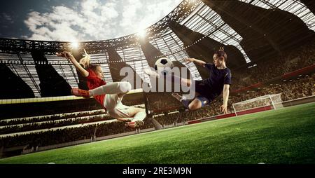 Professional female football players in motion during tense game, hitting ball, playing on 3D open air stadium. Blurred audience Stock Photo