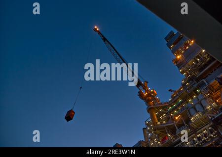 Jack up rig crane lifts container during cargo operations in the sea. Stock Photo