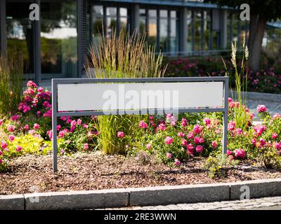 Blank signboard in front of an office building exterior. Empty template for a mockup of a company name and logo sign. Guide to the entrance. Stock Photo