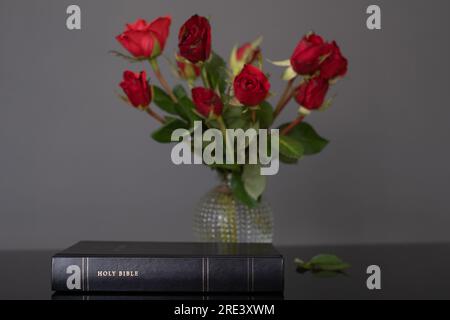 Holy Bible and red roses on the table. Christian concept, copy space Stock Photo