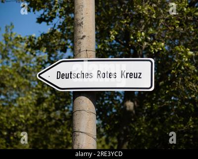 Guiding street sign with the letters Deutsches Rotes Kreuz (German Red Cross). The arrow is pointing to the left. The organisation is providing health Stock Photo