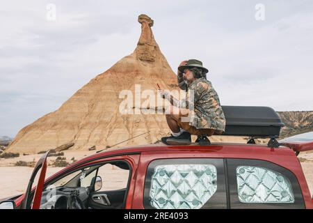 Man looking at cell phone in desert landscape of Bardenas Reales, Arguedas, Navarra, Spain Stock Photo