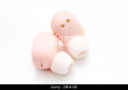 Light pink colored in-ear wireless earphones on white Stock Photo