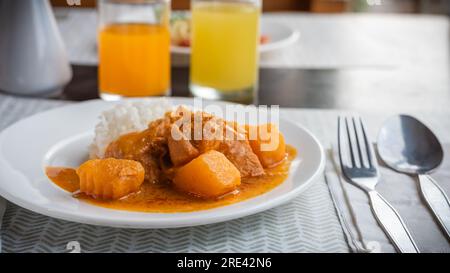 Thai massaman chicken curry with rice on wood table backgrounds Stock Photo