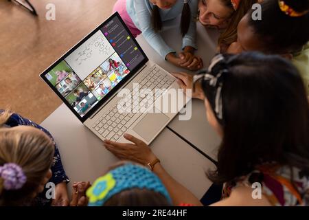 Multiracial teacher and students looking at laptop while studying online over video call on table Stock Photo