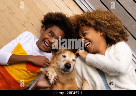 Happy african american mother and son lying on floor with their pet dog Stock Photo