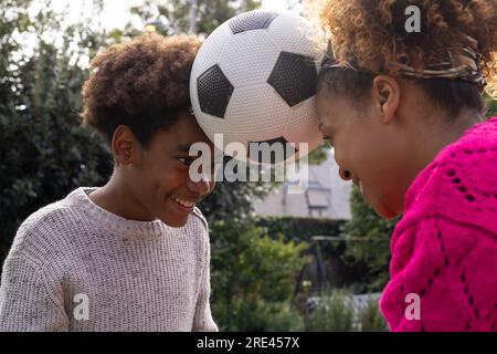 Happy african american mother and son holding ball with heads in garden Stock Photo