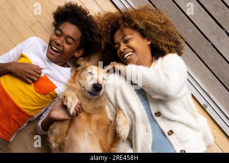 Happy african american mother and son lying on floor with their pet dog Stock Photo