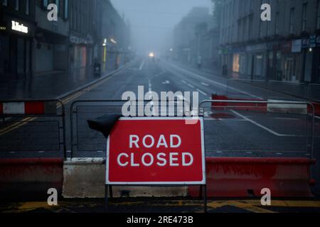 Road closed sign in empty city with street lights. Stock Photo