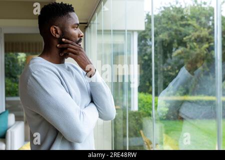 Thoughtful african american man looking out window at home Stock Photo