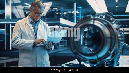 Middle Aged Industrial Turbine Specialist Working on an Innovative Invention. Scientist Using a Laptop Computer to Develop a High Tech Prototype Stock Photo