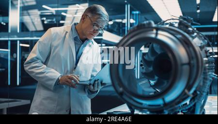 Middle Aged Industrial Turbine Specialist Working on an Innovative Invention. Scientist Using a Laptop Computer to Develop a High Tech Prototype Stock Photo