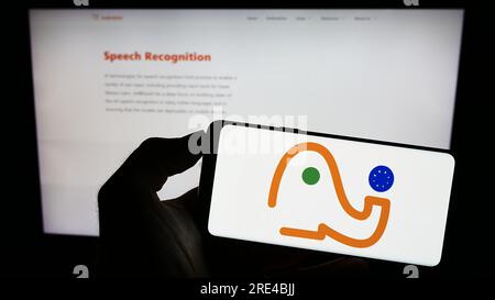 Person holding cellphone with logo of Indian AI initiative AI4Bharat on screen in front of webpage. Focus on phone display. Stock Photo
