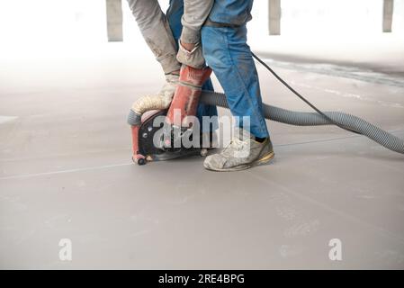 Crop anonymous man leveling floor with machine during construction Stock Photo