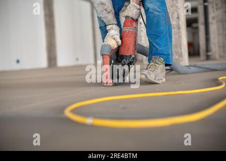 Crop site worker using concrete cutter Stock Photo