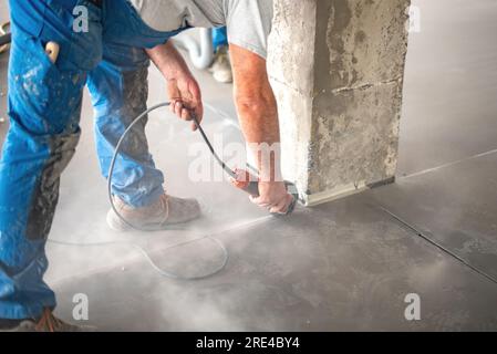 Crop worker cutting concrete with angle grinder Stock Photo