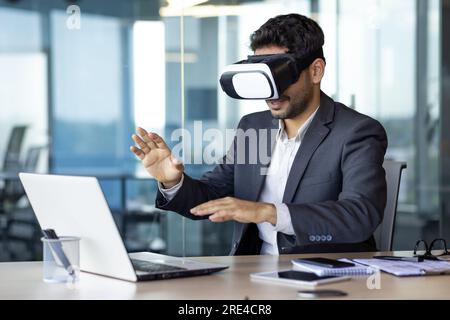 Businessman using vr glasses to view educational material and financial documents, graphs and tables online, financier inside office at workplace. Stock Photo