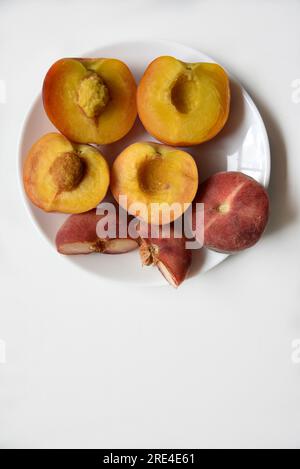 Nectarine and peaches cut into slices on a white plate. Vegetarian food. Stock Photo