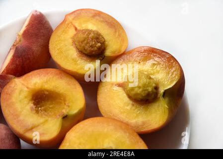 Nectarine and peaches cut into slices on a white plate. Vegetarian food. Stock Photo