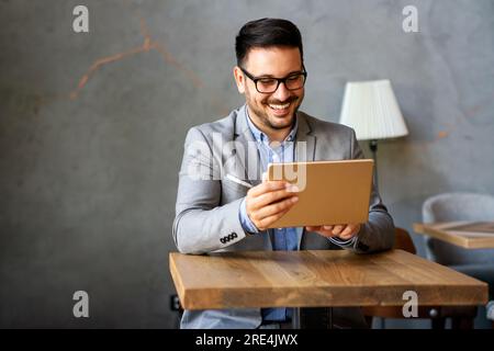Portrait of young successful businessman with digital device working in corporate business office Stock Photo