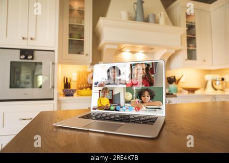 Laptop with video conference with diverse students on a table in the kitchen Stock Photo