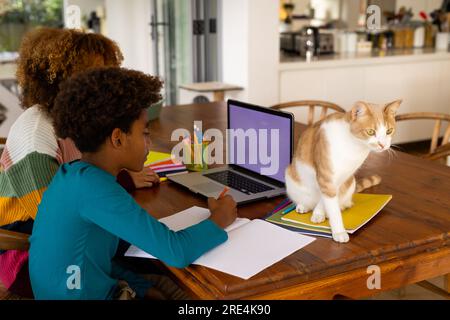 Happy african american mother and son using laptop with copy space, doing homework Stock Photo