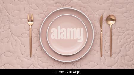 Festive table setting on beige tablecloth. Empty plate, gold cutlery, textile background. Dining in luxury restaurant, view from above. Menu template, Stock Photo