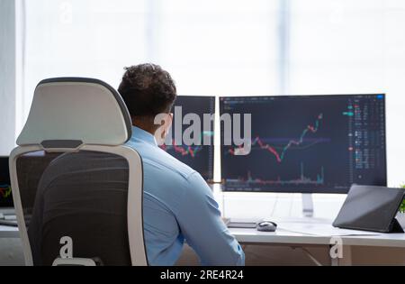 Shoulder shot of professional trader analyzing charts on monitor at office - concept of Technical Analysis, Professional investor and Risk Management Stock Photo