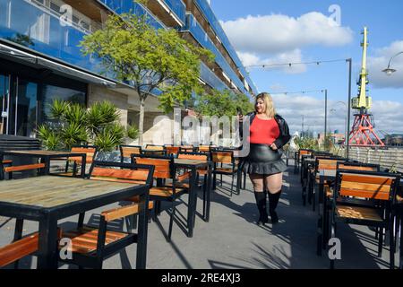 young plus size argentinian latin woman in red and black clothes arriving at outdoor restaurant and going using phone, copy space Stock Photo
