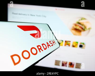 Mobile phone with logo of American food delivery company DoorDash Inc. on screen in front of website. Focus on center-right of phone display. Stock Photo