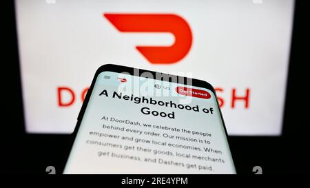 Smartphone with website of US food delivery company DoorDash Inc. on screen in front of business logo. Focus on top-left of phone display. Stock Photo